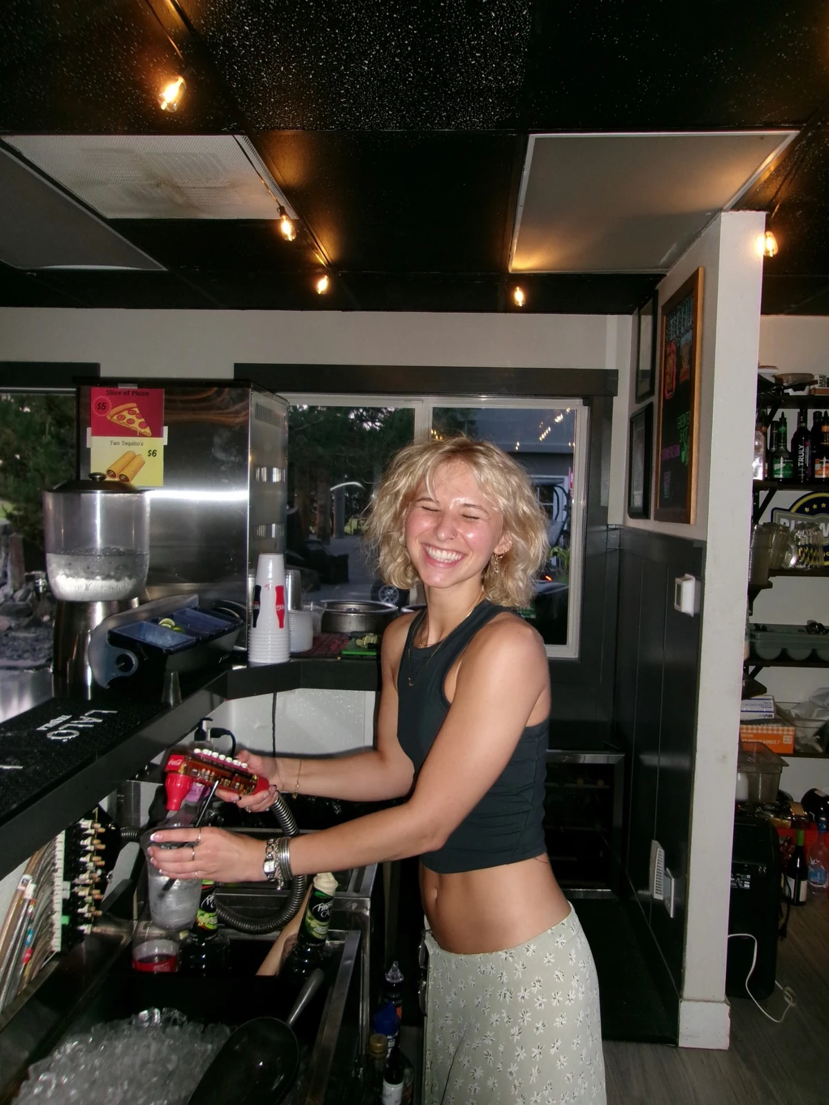 A smiling person behind the Rewsters bar