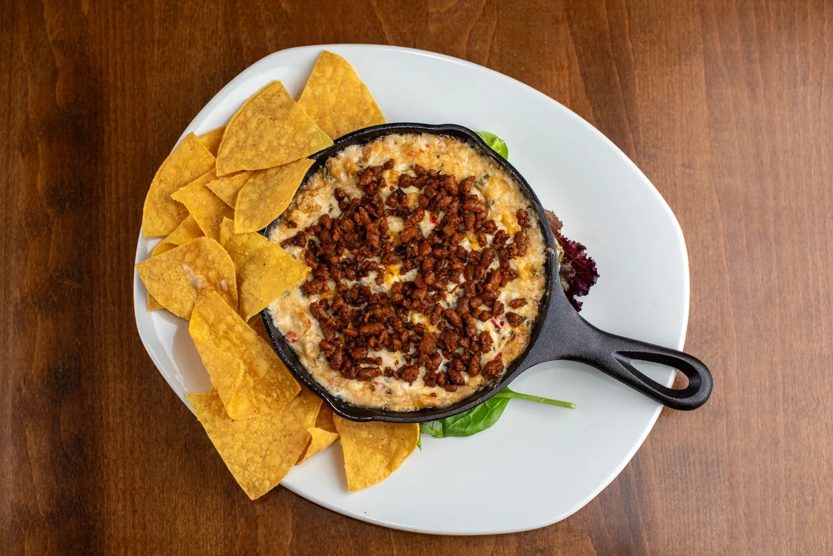 Elote dip served in a cast iron skillet with tortilla chips