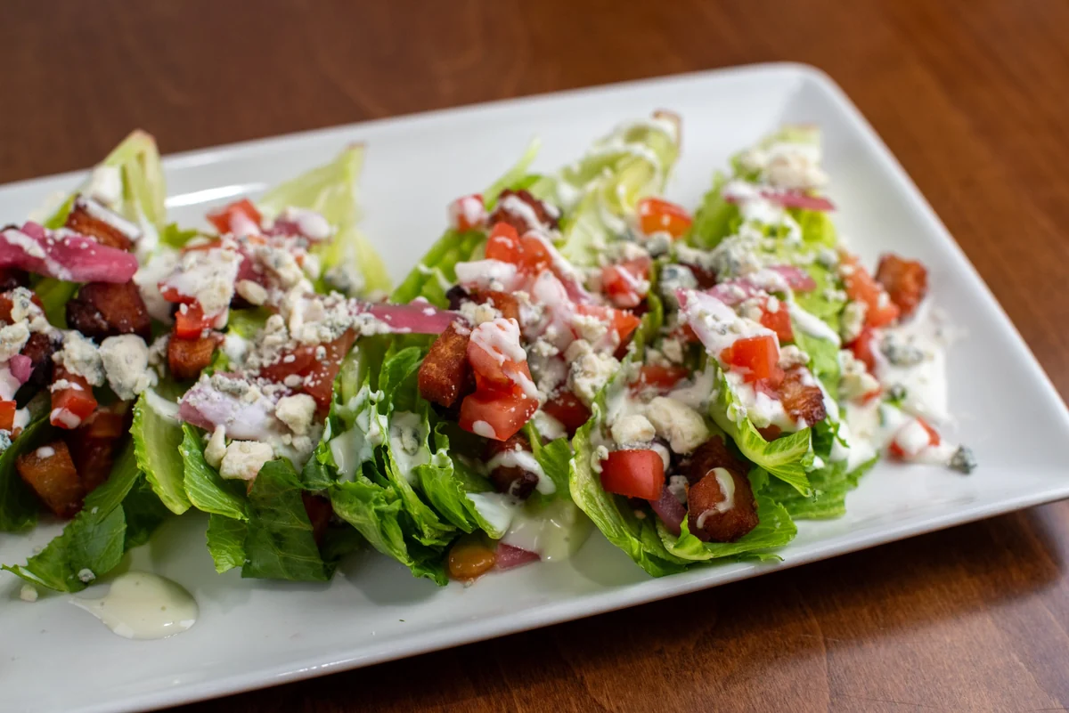 Mini wedge salads with bacon, tomatoes, pickled onions, and crumbled cheese