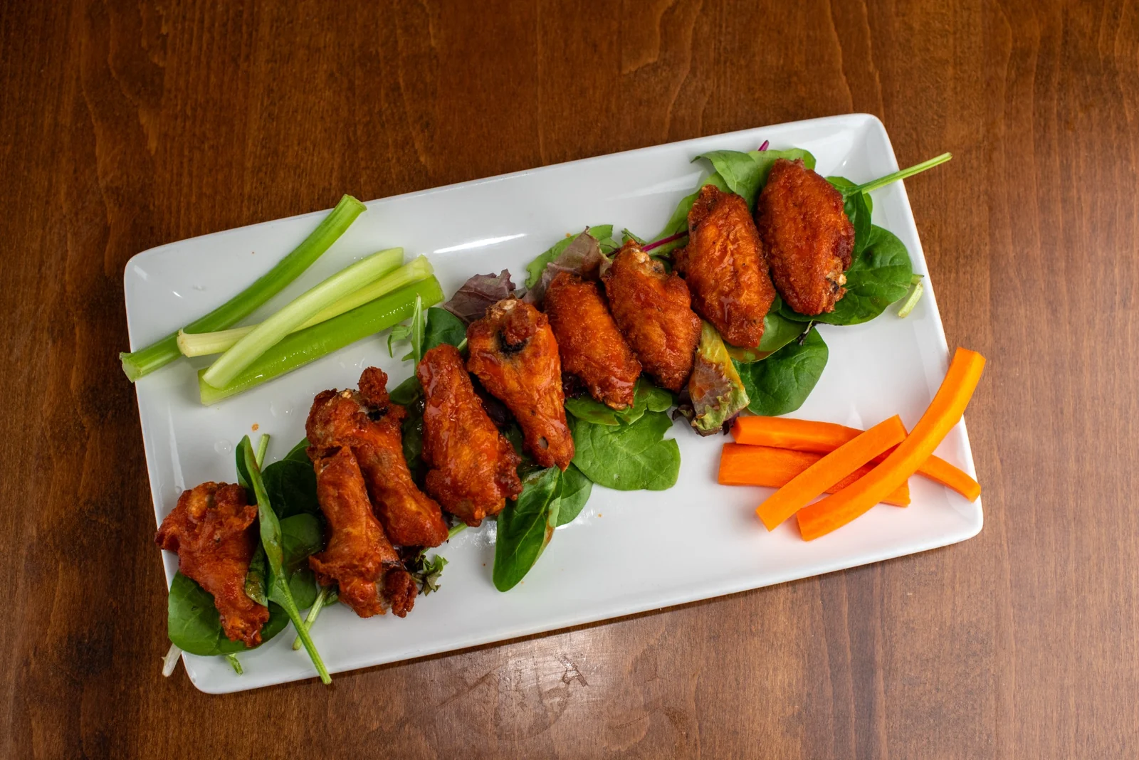Rewsters bone-in wings with celery and carrots on a warm wood table